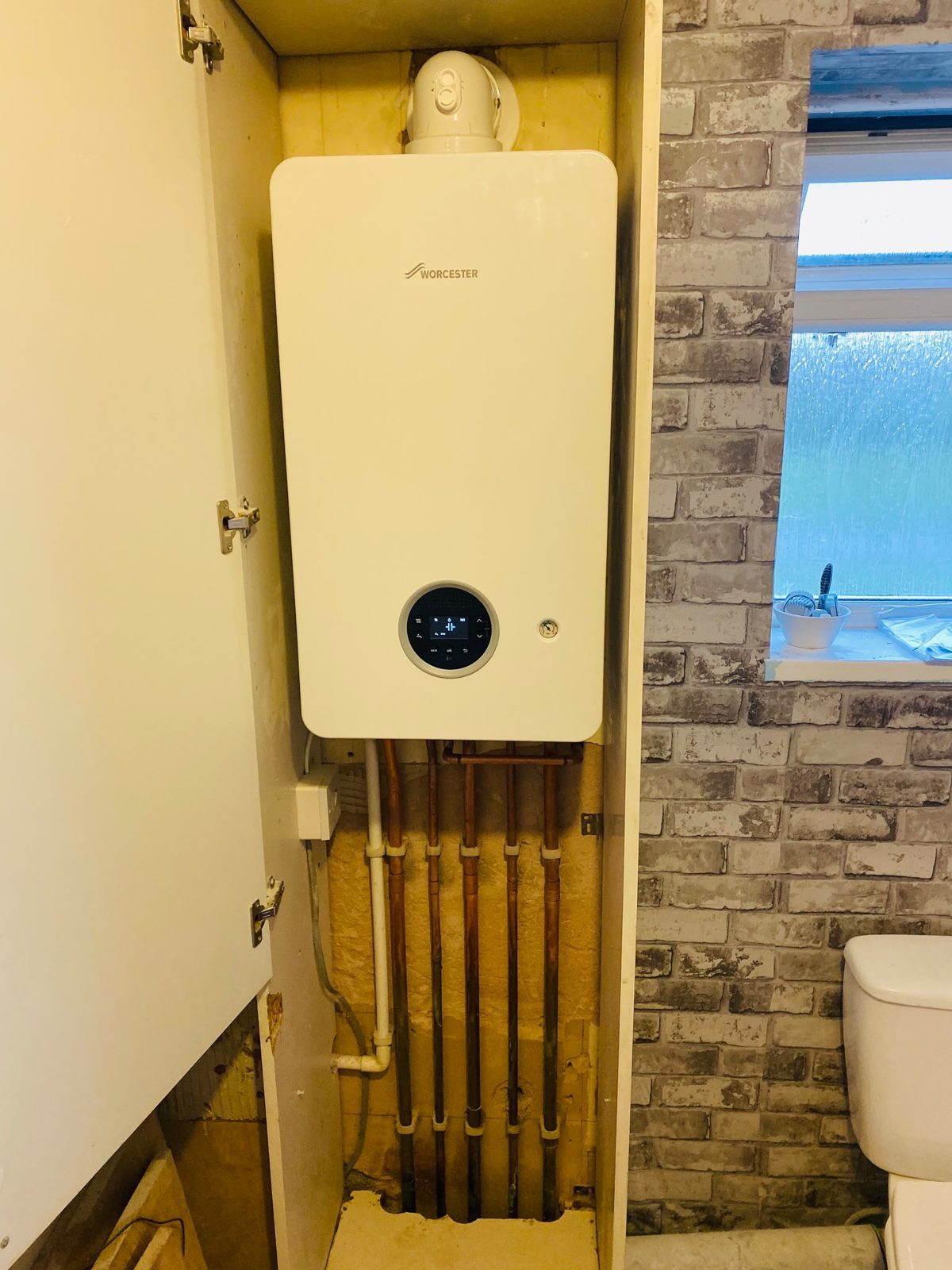 Worcester Greenstar 2000 boiler installed inside an existing cupboard in Stockwood, Bristol, with copper pipework beneath